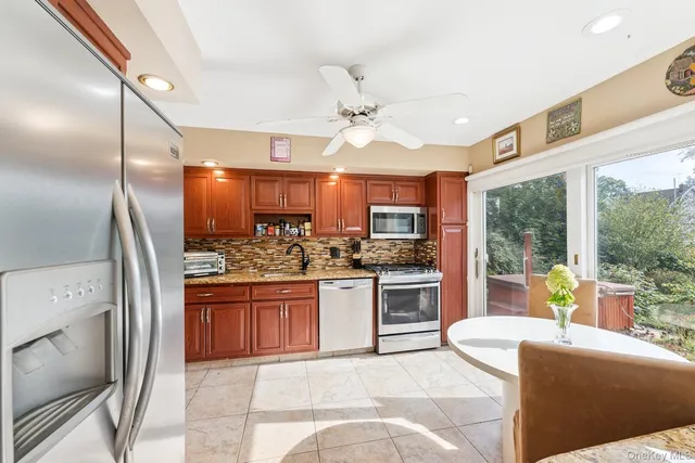 a large kitchen with kitchen island granite countertop a large counter top stainless steel appliances and a large window