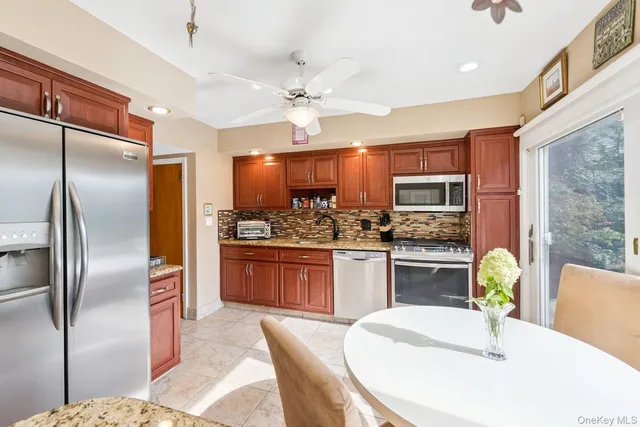 a kitchen with stainless steel appliances kitchen island granite countertop a refrigerator a sink a stove a dining table and chairs with wooden floor