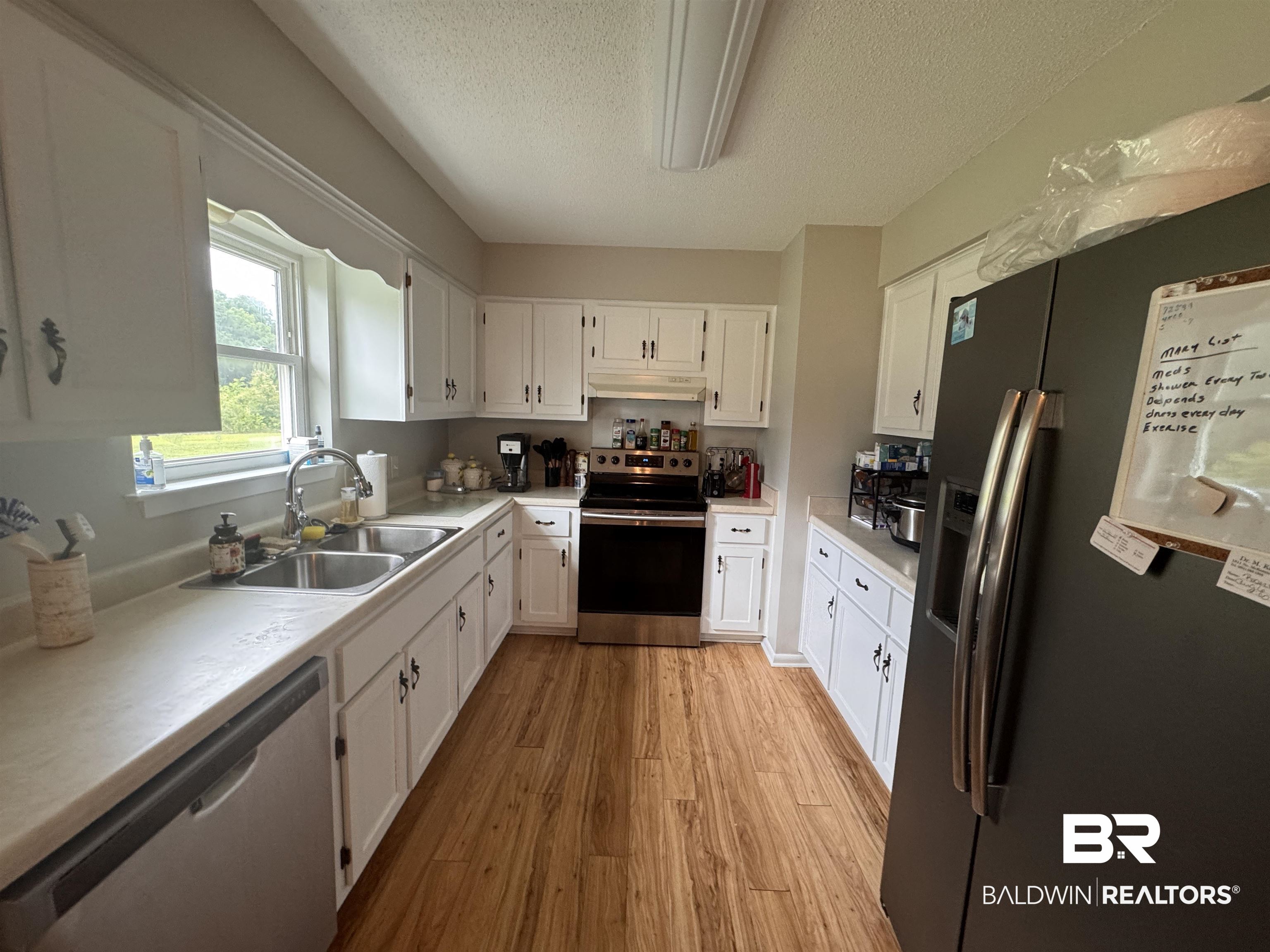 15148 Highland Circle Foley, AL 36535 - Photo 19 of 47 Kitchen with stainless steel appliances, a sink, under cabinet range hood, light wood-style flooring, and a textured ceiling