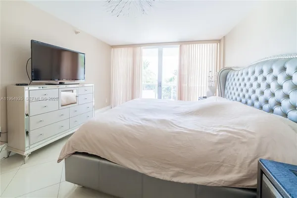 a bed sitting in a bedroom next to a window and a chandelier