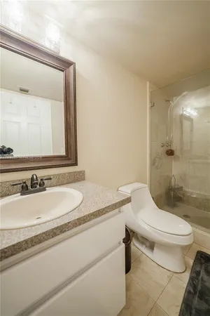 a bathroom with a granite countertop sink mirror vanity and toilet