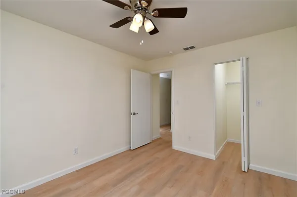 an empty room with wooden floor ceiling fan and windows