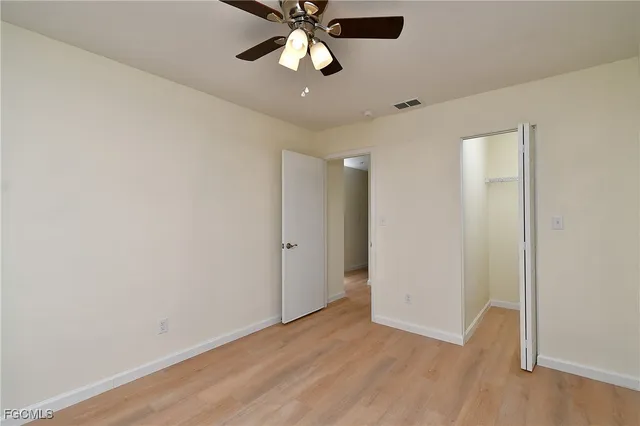 an empty room with wooden floor ceiling fan and windows