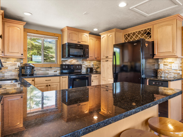 371 Lewis Loop, Unit 29 Fish Haven, ID 83287 - Photo 24 of 40 Kitchen featuring granite countertops, light wood-finish cabinetry, a stone-finish backsplash, and an integrated wine rack