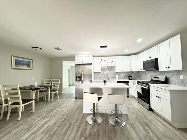 a view of a dining room kitchen wooden floor and stainless steel appliances