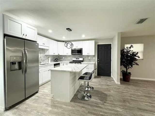 a kitchen with a refrigerator a oven and white cabinets