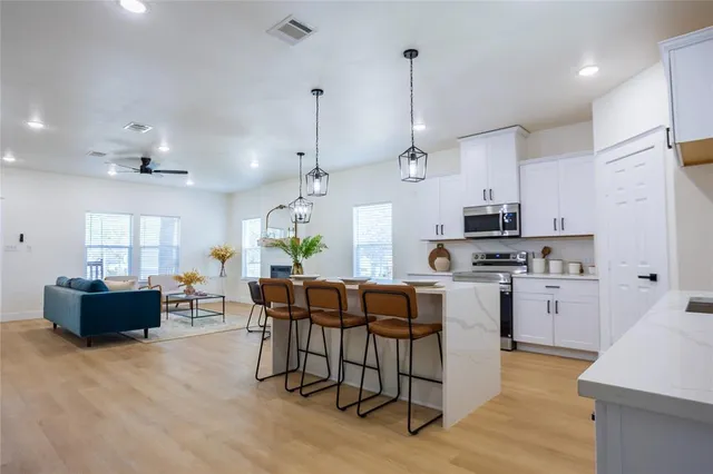 a kitchen with stainless steel appliances kitchen island granite countertop a table chairs and a refrigerator