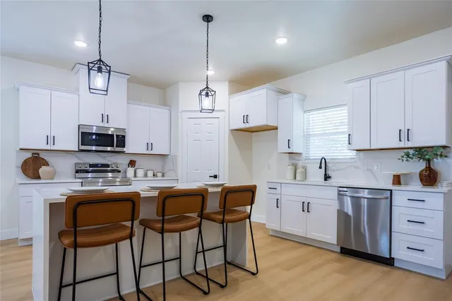a kitchen with stainless steel appliances granite countertop a sink a stove a refrigerator cabinets and chairs