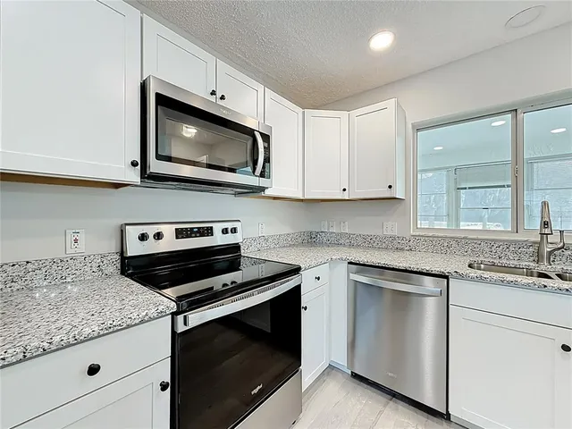a kitchen with white cabinets appliances and a sink