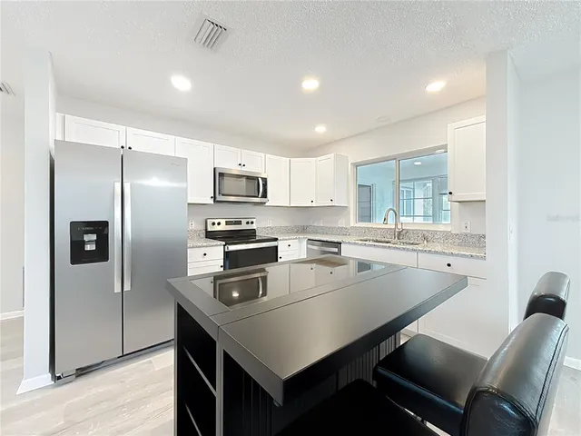a kitchen with kitchen island a stove a sink a refrigerator and cabinets