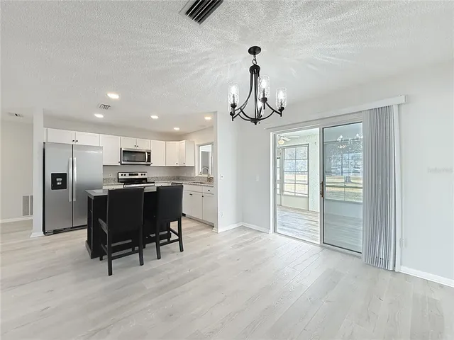 a view of a dining room and livingroom with furniture wooden floor a chandelier