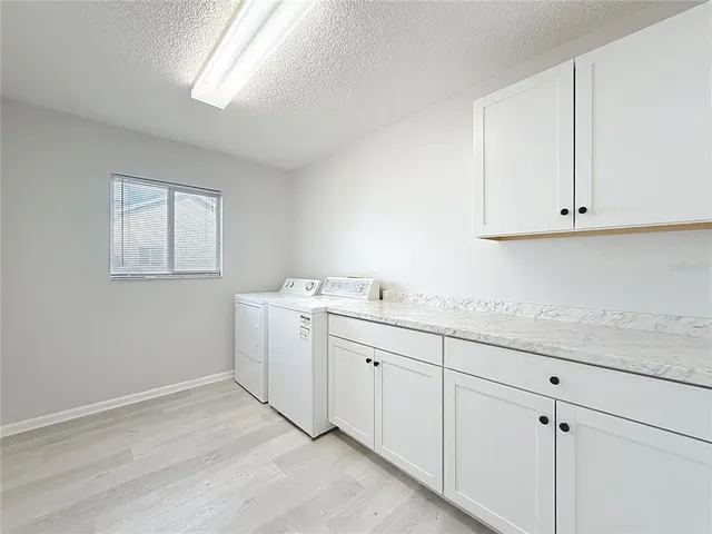 a room with white cabinets appliances and a window