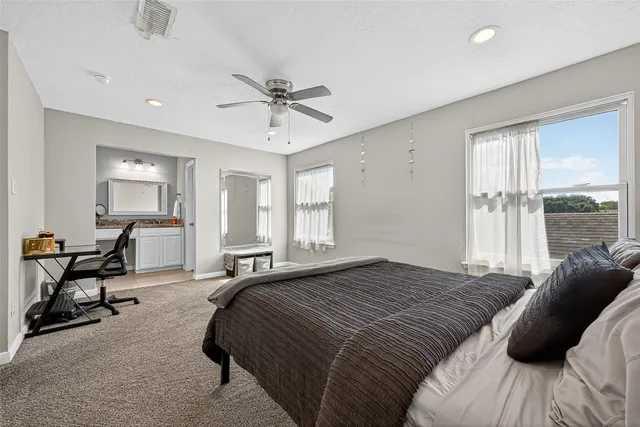 a spacious bedroom with a bed a table and large windows