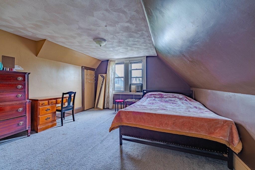 96 Clark Street Everett, MA 02149 - Photo 18 of 26 a bedroom with a bed and a dresser next to a window