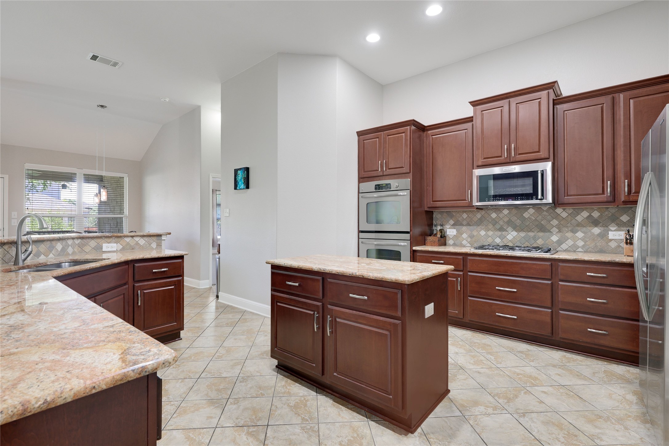 433 Ridgetop Bend Cedar Park, TX 78613 - Photo 13 of 34 Kitchen with a center island, stainless steel appliances, light stone counters, lofted ceiling, and backsplash