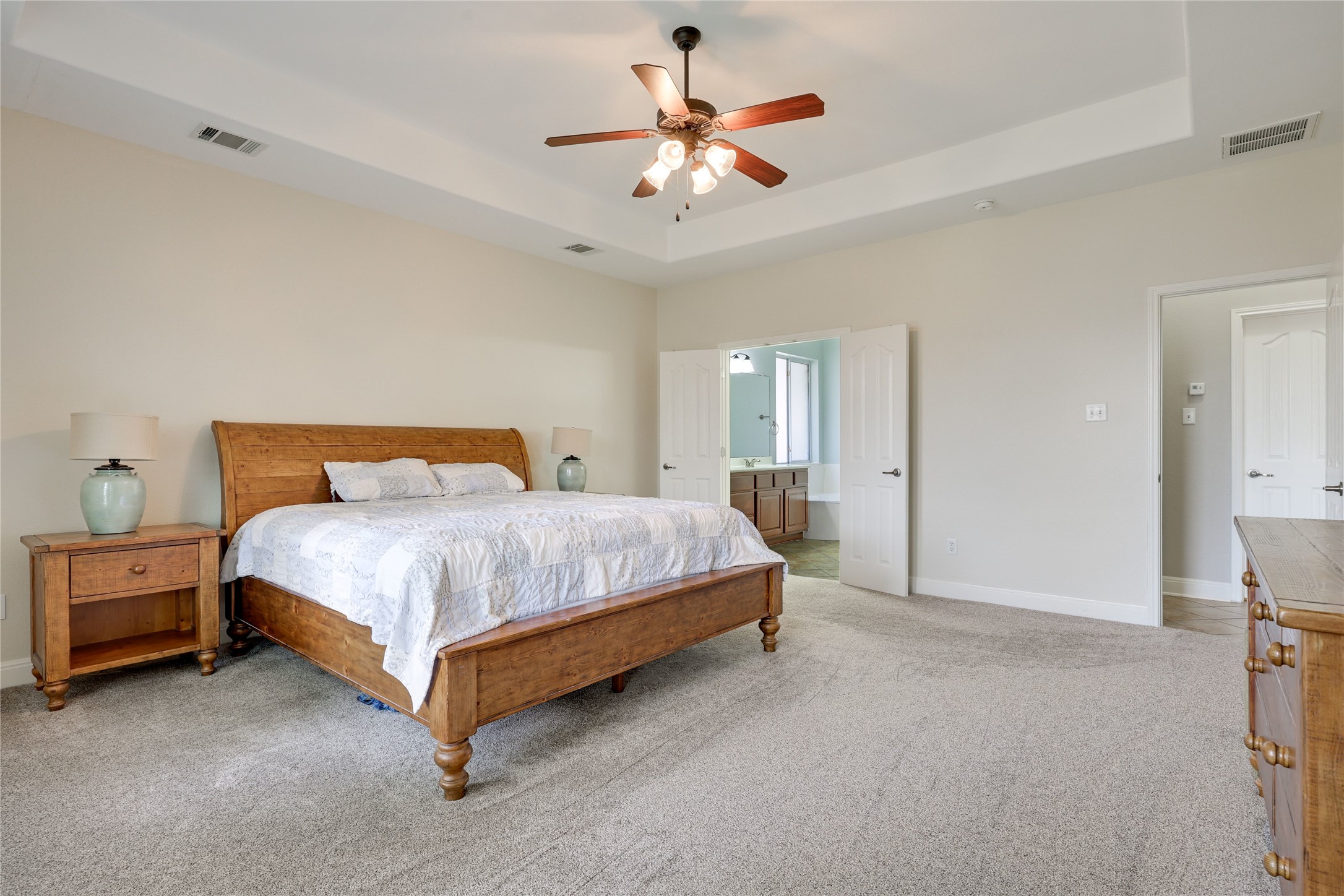 433 Ridgetop Bend Cedar Park, TX 78613 - Photo 20 of 34 Bedroom featuring a raised ceiling, light colored carpet, a ceiling fan, and ensuite bath
