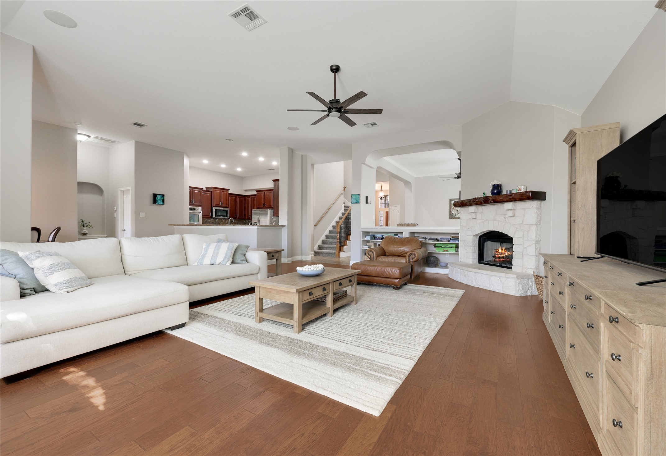 433 Ridgetop Bend Cedar Park, TX 78613 - Photo 3 of 34 Living area featuring arched walkways, ceiling fan, a stone fireplace, dark wood finished floors, and vaulted ceiling