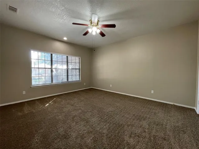 an empty room with chandelier fan and windows