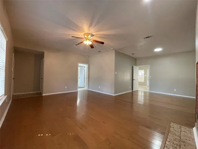 a view of an empty room with a window and wooden floor