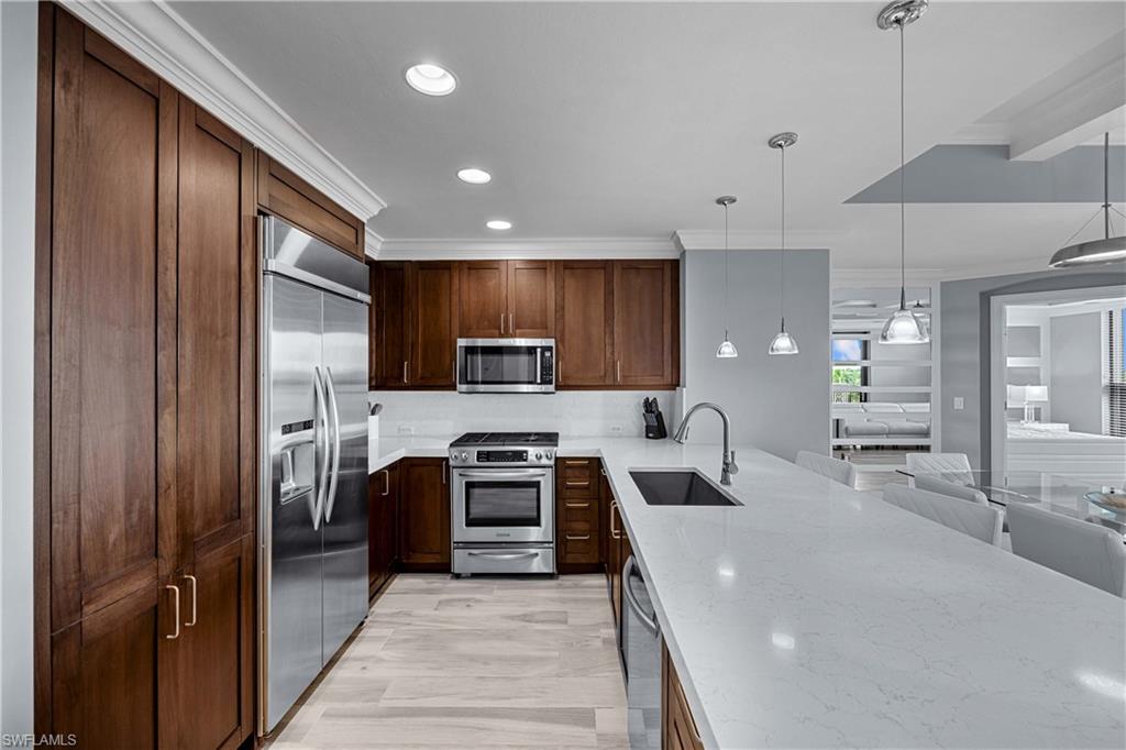 9115 Strada Place, Unit 5511 Naples, FL 34108 - Photo 8 of 38 a kitchen with stainless steel appliances granite countertop wooden cabinets a stove top oven a sink and dishwasher