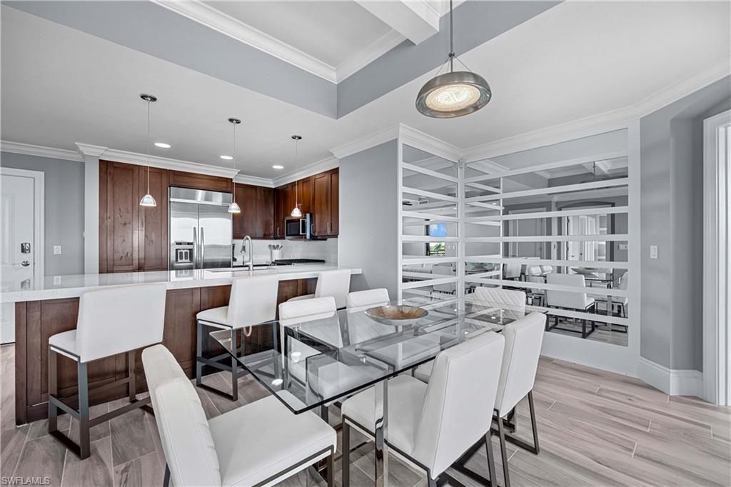 9115 Strada Place, Unit 5511 Naples, FL 34108 - Photo 10 of 38 a kitchen with a dining table chairs and white cabinets