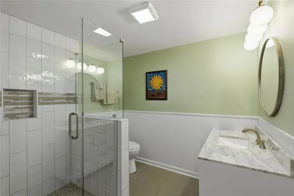 a bathroom with a granite countertop sink a mirror and shower