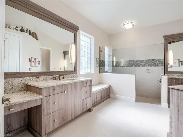 a bathroom with a granite countertop sink mirror and window