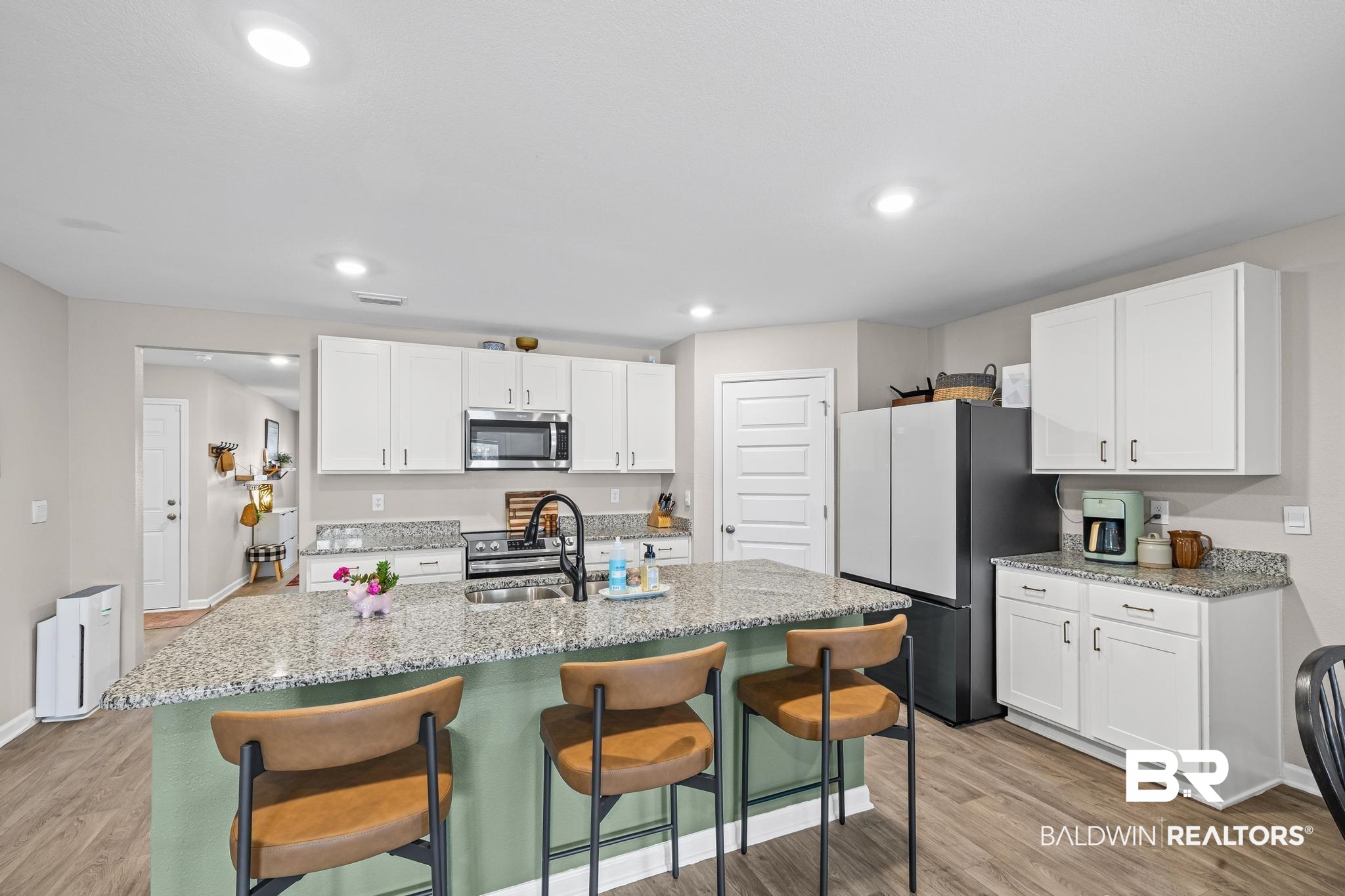 3078 Camino Real Loop Lillian, AL 36549 - Photo 6 of 51 Kitchen featuring white cabinetry, light stone counters, stainless steel appliances, light wood-style floors, and a kitchen bar
