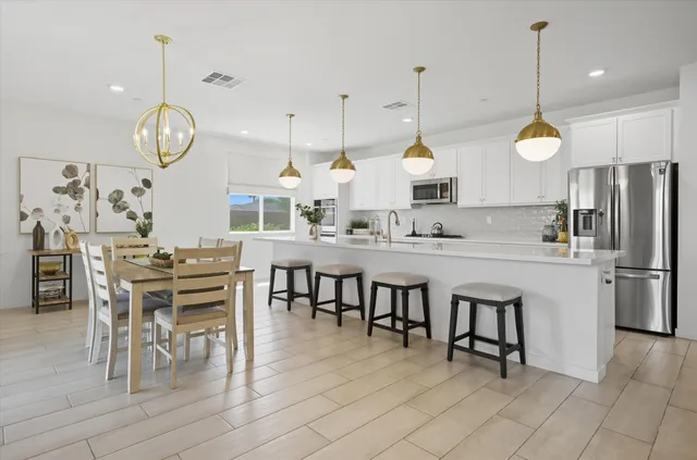a kitchen with stainless steel appliances granite countertop a table chairs sink and cabinets