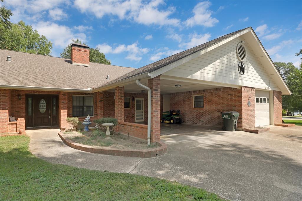 16223 Big Oak Bay Road Tyler, TX 75707 - Photo 8 of 30 View of front of house featuring concrete driveway, an attached carport, a shingled roof, a chimney, and brick siding