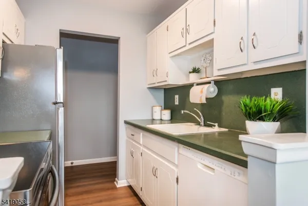 a kitchen with stainless steel appliances granite countertop a sink a refrigerator and a white cabinets