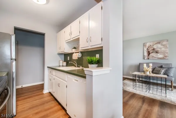 a kitchen with stainless steel appliances a white cabinets and wooden floor