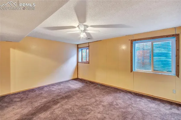 an empty room with chandelier fan and windows