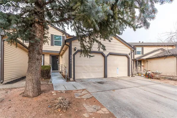 a view of a white house with a large tree