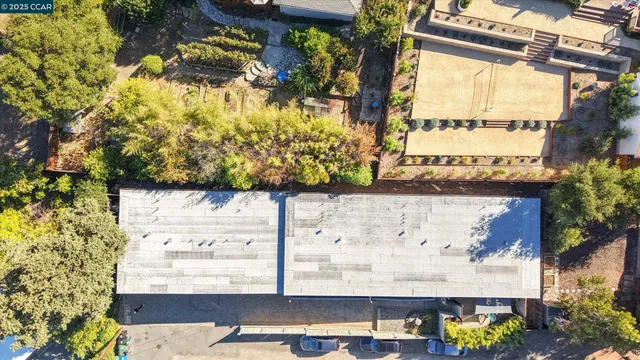 a view of a house with a barbeque and large trees