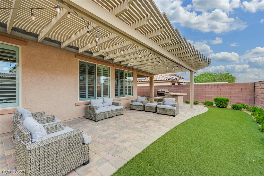 7049 Motley Road Las Vegas, NV 89178 - Photo 50 of 61 A spacious paved patio rests beneath an open-slat pergola alongside a manicured lawn.