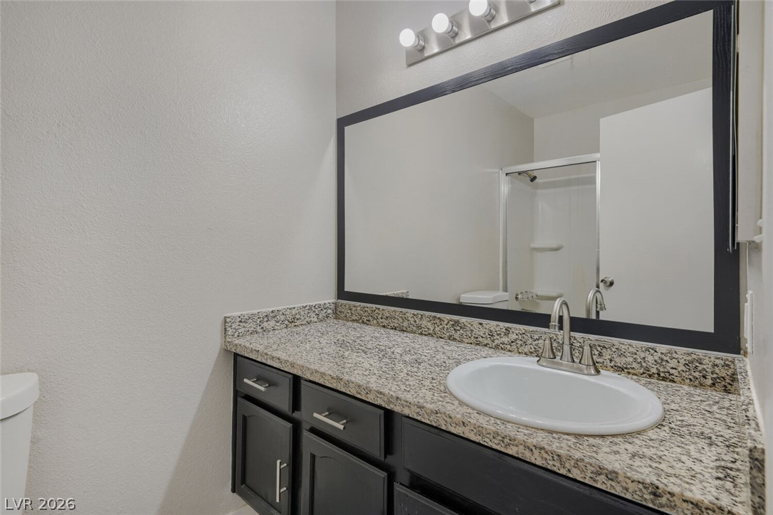 2343 Valleywood Road Henderson, NV 89014 - Photo 22 of 29 A sleek vanity with granite counters and a large mirror defines this functional bathroom.