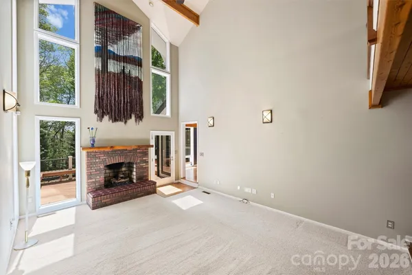 an empty room with windows and fireplace