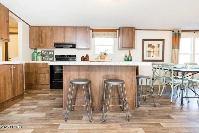 a kitchen with stainless steel appliances granite countertop a stove top oven a sink a dining table and chairs with wooden floor