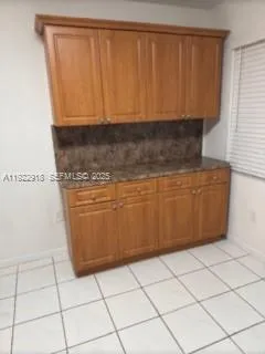 a view of a refrigerator in kitchen and an empty room