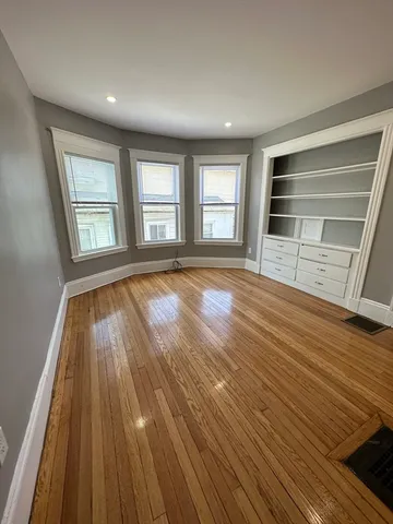 a view of an empty room with wooden floor and window