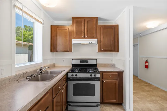 a kitchen with sink a stove and wooden cabinets
