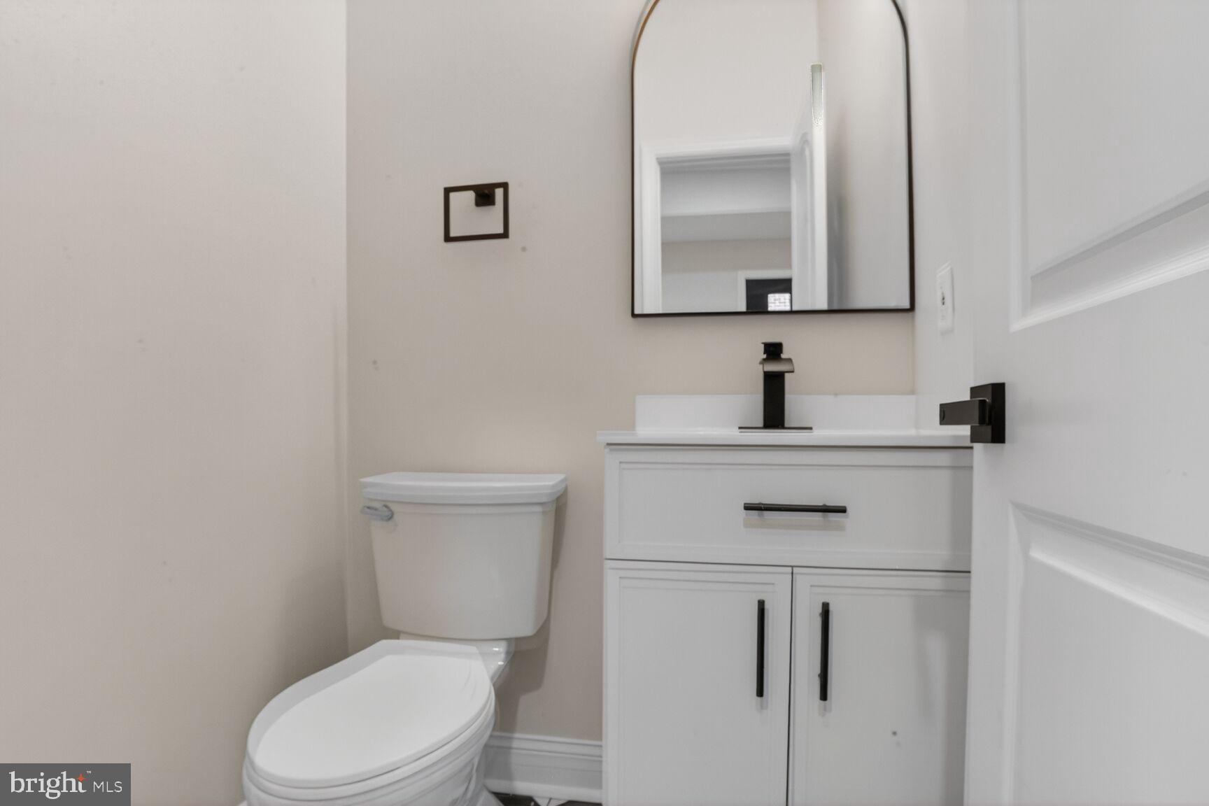 4013 4th Street Baltimore, MD 21225 - Photo 12 of 35 a bathroom with a toilet sink vanity and mirror