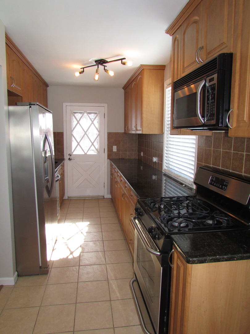 309 East Golf Road Des Plaines, IL 60016 - Photo 11 of 27 a kitchen with stainless steel appliances granite countertop a stove a sink and a microwave