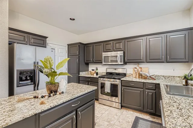 a kitchen with stainless steel appliances granite countertop a sink stove and refrigerator