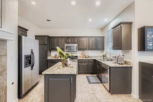 a kitchen with stainless steel appliances granite countertop a sink stove refrigerator and cabinets