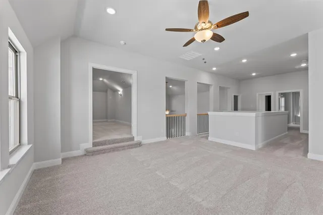 a view of a livingroom with a ceiling fan & kitchen view