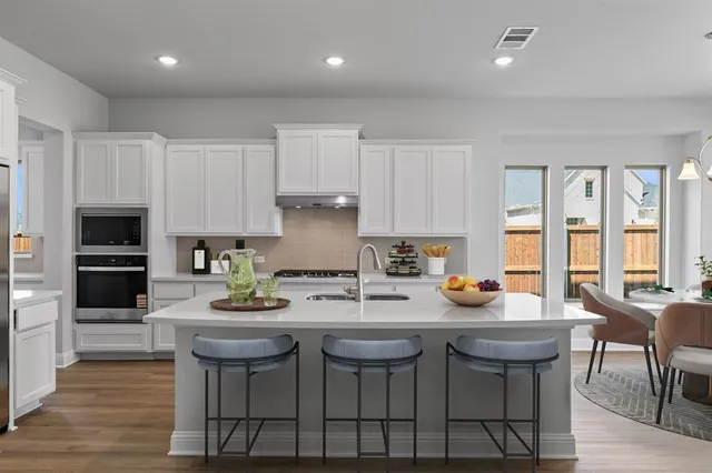 a kitchen with stainless steel appliances granite countertop a table chairs stove microwave and cabinets