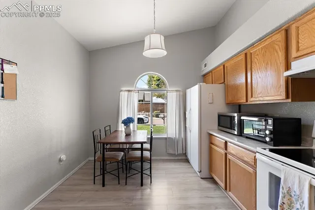 a kitchen with stainless steel appliances granite countertop a stove a refrigerator a kitchen island a dining table and chairs with wooden floor