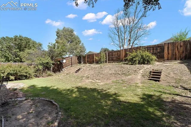 a view of backyard with wooden fence